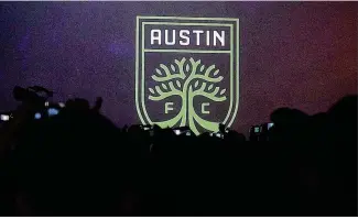  ?? NICK WAGNER / AMERICAN-STATESMAN ?? The badge for Austin’s new MLS team, Austin FC, is unveiled to supporters at the North Door in East Austin on Wednesday night.