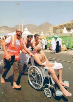  ?? — AFP ?? Emergency personnel and Haj pilgrims help a person wounded in a stampede in Mina on Thursday.