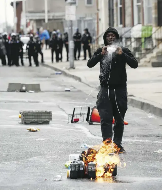  ?? Drew Angerer / Gett y Images ?? A man pours lighter fluid on debris during a riot in Baltimore on Monday.