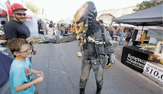  ??  ?? TOP: Brody Long, 9, of Roswell smiles as Ed Cook of Roswell, dressed as the Predator, pats his head Saturday in Roswell during the annual UFO Festival.