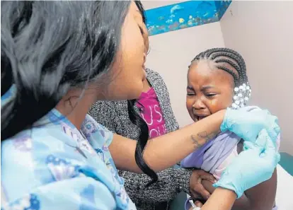  ?? ALGERINA PERNA/BALTIMORE SUN ?? Paige Matthews gets a flu shot this week from Karmalla Johnson, medical assistant at MedStar Union Memorial Hospital. Holding Paige is her grandmothe­r, Sharon Robinson, who lives with Paige and her mother and said Paige soon forgot about the shot.