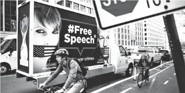  ?? — AFP photo ?? In this file, cyclists pass a truck with a protest sign on it reading “#FreeSpeech” with pictures of Manning (left) and Assange, in Washington, DC.