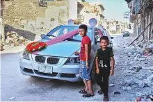  ??  ?? Children stand next to a car that has been decorated for the first wedding in Mosul a year after it was liberated.