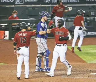  ?? ROB SCHUMACHER/THE REPUBLIC ?? The Diamondbac­ks’ Wyatt Mathisen, right, crosses home plate after homering against the Rangers in the sixth inning at Chase Field in Phoenix on Wednesday. Arizona won 7-3.