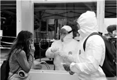  ?? AP Photo/Marcio Jose Sanchez ?? In this April 20 file photo, members of the Los Angeles Fire Department wear protective equipment as they conduct a new coronaviru­s test on a woman, left, in the Skid Row district in Los Angeles.