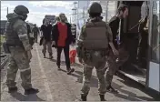  ?? RUSSIAN DEFENSE MINISTRY PRESS SERVICE ?? In this photo taken from video released Tuesday, Russian servicemen watch Ukrainian servicemen boarding a bus as they are being evacuated from the besieged Azovstal steel plant in Mariupol, Ukraine.