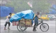  ?? ANI ?? Workers cover a cart with a plastic sheet while commuting amid heavy rainfall in Kolkata on Tuesday.