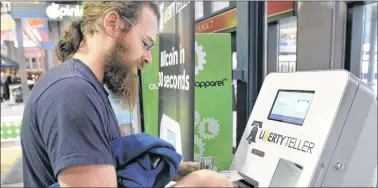  ??  ?? STEVEN SENNE/THE ASSOCIATED PRESS In this March 31, 2014, file photo, Tim Mccormack, of Boston, inserts cash into a Liberty Teller ATM while purchasing bitcoins at South Station train station, in Boston. On Thursday, Bitcoin tumbled 15 percent to about...