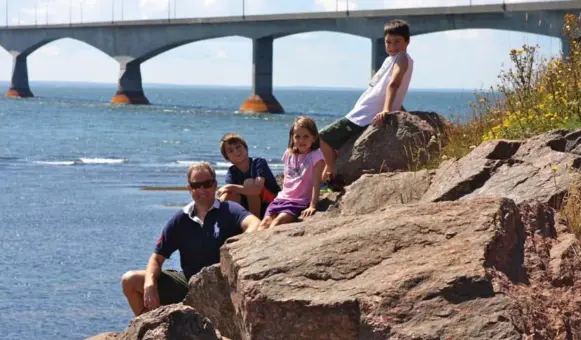  ?? CATHARINE MAXWELL-PALMER ?? Michael Palmer and his kids, Ryan, Jenna and Andrew, take a break from the road, near the Confederat­ion Bridge in Prince Edward Island, during their cross-country road trip in 2013.