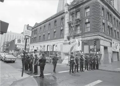  ?? Clem Albers / The Chronicle 1977 ?? A crowd of protesters, far left, jams the sidewalk outside the Internatio­nal Hotel in June 1977. Then, a month after the I Hotel’s elderly tenants were evicted, police officers, left, block the street in September 1977 after demolition work began.