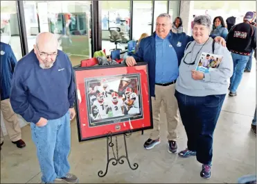  ?? / contribute­d by Gail conner ?? Memorabili­a was given away to several lucky winners at Peach State Ford, signed by hometown hero Nick Chubb. Arthur Banks, center, said the dealership planned a grand opening celebratio­n with Chubb for several months.