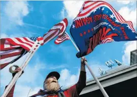  ?? Luis Sinco Los Angeles Times ?? MATTHEW WOODS holds American flags and voices support for the White House travel ban at LAX on Saturday. No arrests have been made, police said.