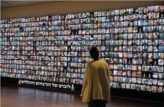  ?? /Amir Levy/Getty Images ?? State of mourning: A woman looks at a screen of photos of those killed during the October 7 Hamas attacks and soldiers killed in the war in Gaza at the National Library of Israel on Sunday in Jerusalem, Israel.