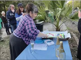  ?? PHOTOS BY JENNIE BLEVINS — ENTERPRISE-RECORD ?? Habitat for Humanity homeowner Pam Halstead cuts the cake at the celebratio­n held Thursday to commemorat­e her paying off the mortgage at her home on Ivy Street in Chico.