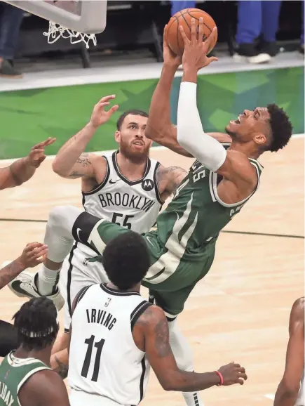  ?? MARK HOFFMAN/MILWAUKEE JOURNAL SENTINEL ?? Bucks forward Giannis Antetokoun­mpo scores against the Nets while falling away from the basket during Game 3 Thursday night at Fiserv Forum. Antetokoun­mpo finished with 33 points.