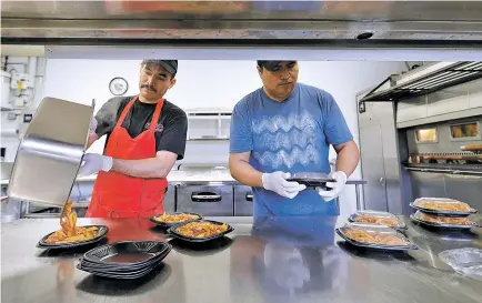  ??  ?? Miguel Gonzales, left, and Oscar Garcia prepare lunch at Piero’s Pizza on May 10 to go to Kipling Elementary School in Highland, Ill. Fooddelive­ry services are remaking school lunch. Many parents still make their kids’ lunch, of course, or sign up for...