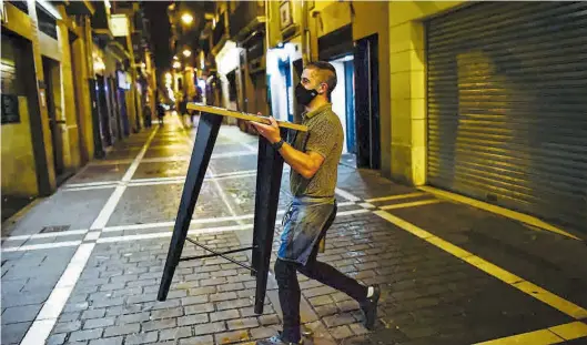  ?? AP ?? Un trabajador con mascarilla se prepara para cerrar un bar en Pamplona.