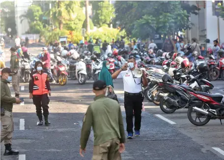  ?? AHMAD KHUSAINI/JAWA POS ?? DIBUBARKAN: Anggota tim Satgas Covid-19 meminta warga yang berkerumun di Tugu Pahlawan kemarin segera pulang ke rumah masing-masing.