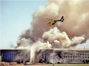  ?? AP PHOTO/HEESOON YIM ?? A helicopter flies over the Pentagon in Washington as smoke billows over the building on Sept. 11, 2001, after a hijacked airliner crashed into the west side, killing 184 people.