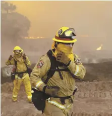  ?? AP PHOTO ?? FEELING THE HEAT: Firefighte­rs cover up from an advancing wildfire’s smoke and ash yesterday in Lakeport, Calif.