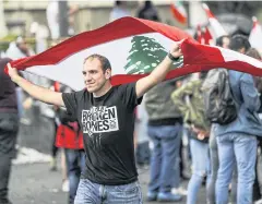  ?? AFP ?? A man walks waving a Lebanese national flag during a demonstrat­ion on the eighth day of protests against tax increases and official corruption.