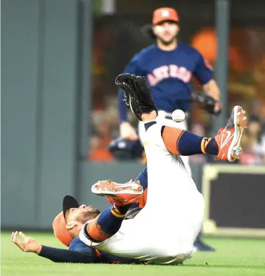  ?? Eric Christian Smith/Associated Press ?? ■ Houston Astros center fielder George Springer, bottom, falls over while trying to catch a shallow fly ball hit by Kansas City Royals' Hunter Dozier during the eighth inning of a baseball game Sunday in Houston.
