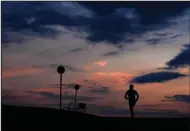  ?? ?? A man jogs as the sun sets at the Olympic park Monday in Munich, Germany. (AP/Matthias Schrader)