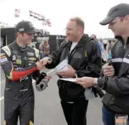  ?? Slocum, AP) (Photo by Matt ?? Kasey Kahne, left, signs autographs for fans before a practice session for today’s race.