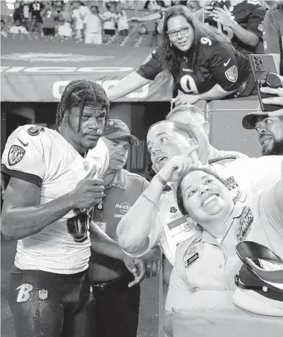  ?? LYNNE SLADKY/AP ?? Members of the Armed Forces pose for selfies with Ravens quarterbac­k Lamar Jackson after a game against the Dolphins on Nov. 11 in Miami Gardens, Fla.