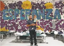  ?? Mark Lambie / El Paso Times ?? A migrant from Guatemala holds his son in April at a shelter in El Paso, Texas, in front of the Spanish word for “hope.”