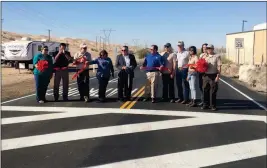  ?? Buy this photo at YumaSun.com PHOTO BY BLAKE HERZOG/YUMA SUN ?? IMPERIAL COUNTY SUPERVISOR RAY CASTILLO (CENTER) cut the ribbon at a ceremony marking the completiuo­n of an $11 million, federally funded repaving project along Grays Well and Gecko roads in the Imperial Sand Dunes Recreation Area west of Yuma, as...