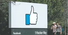  ??  ?? Dos jóvenes caminan junto a un icono de Facebook en Menlo Park, California. La red social dijo que enviaría mensajes a 30 millones de víctimas de los hackers.