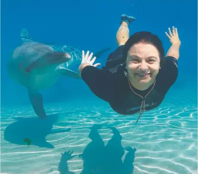  ?? Picture: ADAM HEAD ?? Dolphin trainer Chrissa Athousis swims with Scooter the dolphin at Sea World.