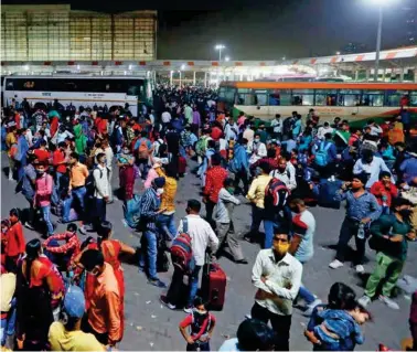  ??  ?? Above: Migrant workers gather at a bus station in Ghaziabad on the outskirts of New Delhi yesterday to board buses to return to their villages after Delhi government ordered a sixday lockdown.