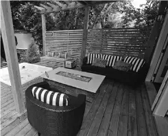  ??  ?? Opposite the outdoor kitchen is a hot tub and covered, comfortabl­e seating area around a smoke-free fire table.