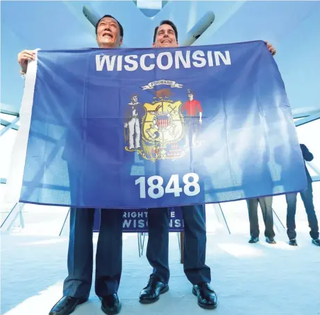  ?? MIKE DE SISTI / MILWAUKEE JOURNAL SENTINEL ?? Foxconn Chairman Terry Gou, left, and Gov. Scott Walker hold up a Wisconsin flag to celebrate the company’s $10 billion investment to build a factory in Wisconsin that could employ up to 13,000 workers. The governor wants to give the company up to $3...