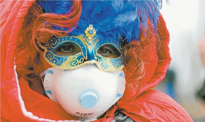  ??  ?? A Venice Carnival reveller wears an extra face mask prior to the final two days of the carnival being cancelled.