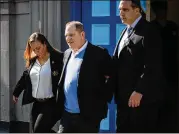  ?? MARK KAUZLARICH / BLOOMBERG ?? Movie mogul Harvey Weinstein is escorted in handcuffs Friday after surrenderi­ng to face charges of rape and sexual abuse in assault cases involving two women.