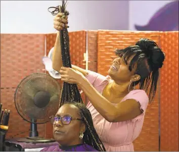  ?? Photograph­s by Gary Coronado Los Angeles Times ?? OWNER KIM DAFNEY prepares the braids of Lisa Jackson of Van Nuys at Kim’s Touch of Class Hair Design in Northridge. “People want simplicity,” says Dafney, “something they can manage all week.”