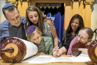  ?? PHOTOS BY JAY JANNER / AMERICAN-STATESMAN ?? Jen Taylor Friedman (right) — a soferet, or Jewish female scribe — and Levi Hurt, 8, together write one of the last letters in a new Torah at Congregati­on Agudas Achim on Sunday. Looking on are Levi’s parents, Brett and Debra Hurt, and sister, Rachel....