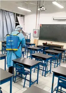  ??  ?? Keeping clean: State Health Department personnel conducting a disinfecti­on exercise at the school in Bukit Jambul.