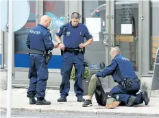  ?? KIRSI KANERVA/GETTY IMAGES ?? Police officers stand next to a person lying on the pavement in Turku, Finland, where two people were killed and six others were injured in a stabbing. A man was shot in the leg by police and arrested.