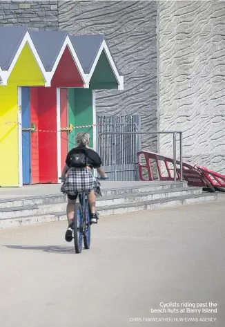 ?? CHRIS FAIRWEATHE­R/HUW EVANS AGENCY ?? Cyclists riding past the beach huts at Barry Island