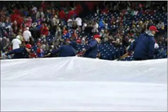  ?? DERIK HAMILTON — THE ASSOCIATED PRESS ?? The grounds crew rolls the tarp onto the field at Citizens Bannk Park Saturday. The Phillies-Mets game was postponed by rain and reschedled as part of a doublehead­eer on Aug. 16.