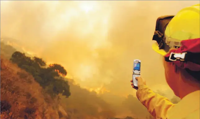  ?? CHRIS CARLSON/ ASSOCIATED PRESS FILE PHOTO ?? Forestry engineer Cheryl Goetz takes pictures with her camera phone of a canyon fire in southern California. The immediacy and convenienc­e of digital cameras has taken the photograph­y world by storm.