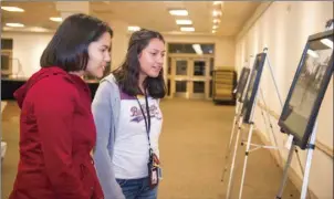  ?? VINCENT OSUNA PHOTO ?? Carolina Lopez (right) and Emilia Ochoa look at a number of exhibits on display during the Calexico Arts Commission’s 2018 Black and White Show in Calexico on Tuesday night.