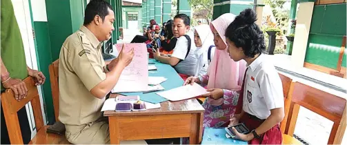  ?? M. FIKRI ZULFIKAR/JAWA POS RADAR KEDIRI. ?? SIAPKAN BERKAS: Para siswa yang diterima masuk ditemani orang tua saat melakukan daftar ulang di SMP Negeri 1 Kota Kediri kemarin.