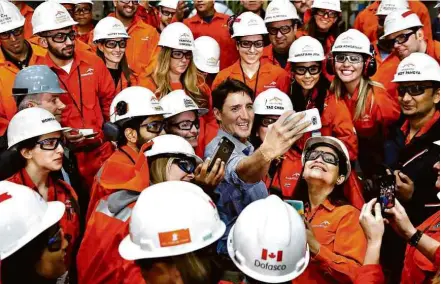  ?? Mark Blinch/Reuters ?? » SELFIE DE AÇO O primeiro-ministro do Canadá, Justin Trudeau, faz fotografia com funcionári­os de unidade da ArcelorMit­tal em Ontário; país ficou livre da sobretaxa imposta ao aço e ao alumínio pelo presidente Donald Trump