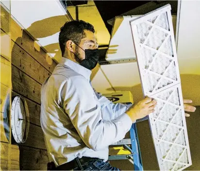  ?? GRANT HINDSLEY NEW YORK TIMES PHOTOS ?? Armando Garcia, a building engineer, installs new air filters in an office building in Seattle in early December.