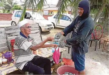  ??  ?? ADNAN (kiri) membayar ikan yang dibelinya daripada Mohd Fazli di Kampung Pantai, Kuala Sungai Baru.